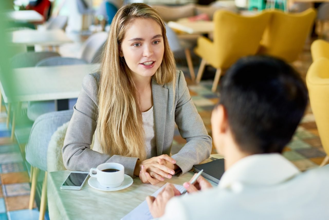 Dos personas de negocio conversando mientras toman un café