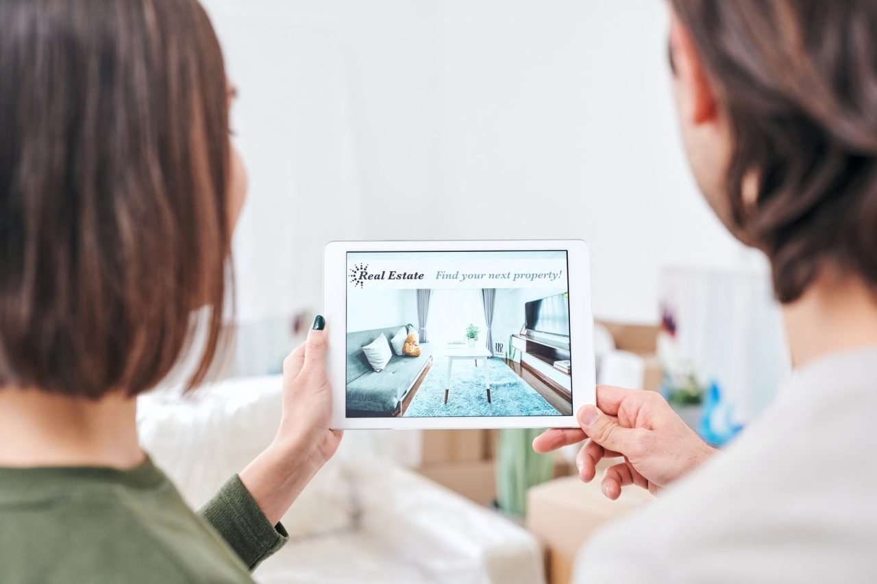 Personas sosteniendo Tablet con imagen de inmobiliaria